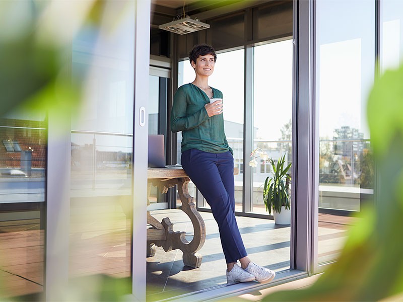 Smiling businesswoman leaning against table having a coffee break