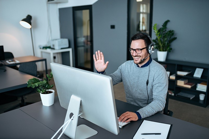 Customer support agent greeting his clients via video call.