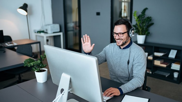 Customer support agent greeting his clients via video call.