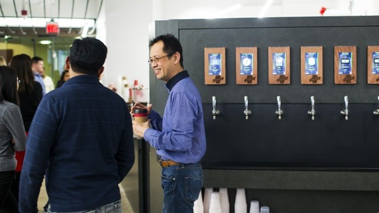 Man taking coffee from Machine and discussing with others