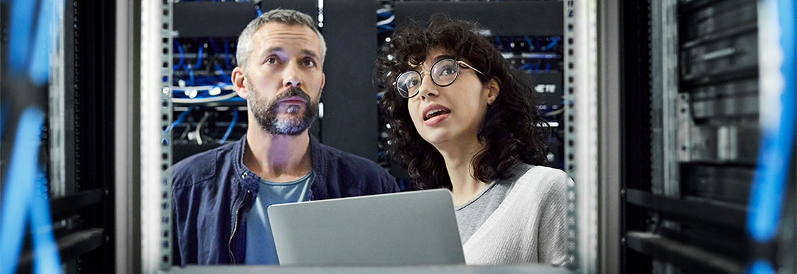 A man and a woman inspecting racks in a data center.