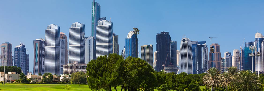 A lush golf course set against a backdrop of towering buildings, illustrating the contrast between greenery and urban life.