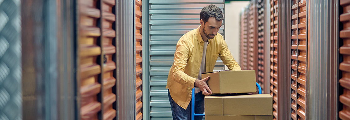 Man loading boxes from a trolley into a self storage unit.