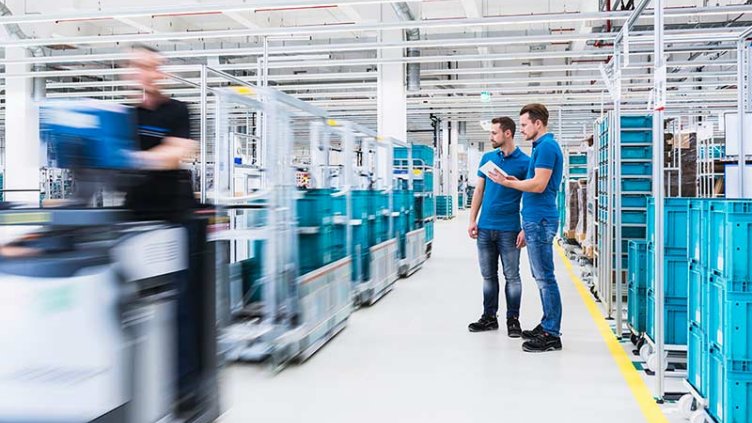 Two men with tablet talking in industrial hall