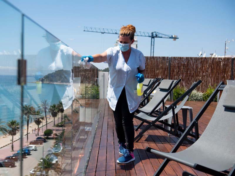 cleaning staff disinfectanting the hotel glass wall during covid