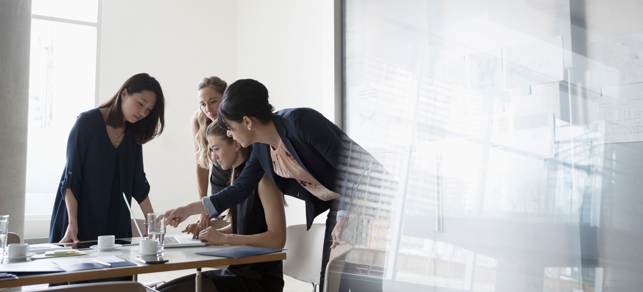 businesswomen brainstorming talking around laptop