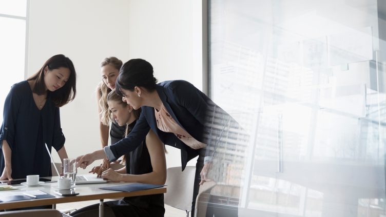 businesswomen brainstorming talking around laptop