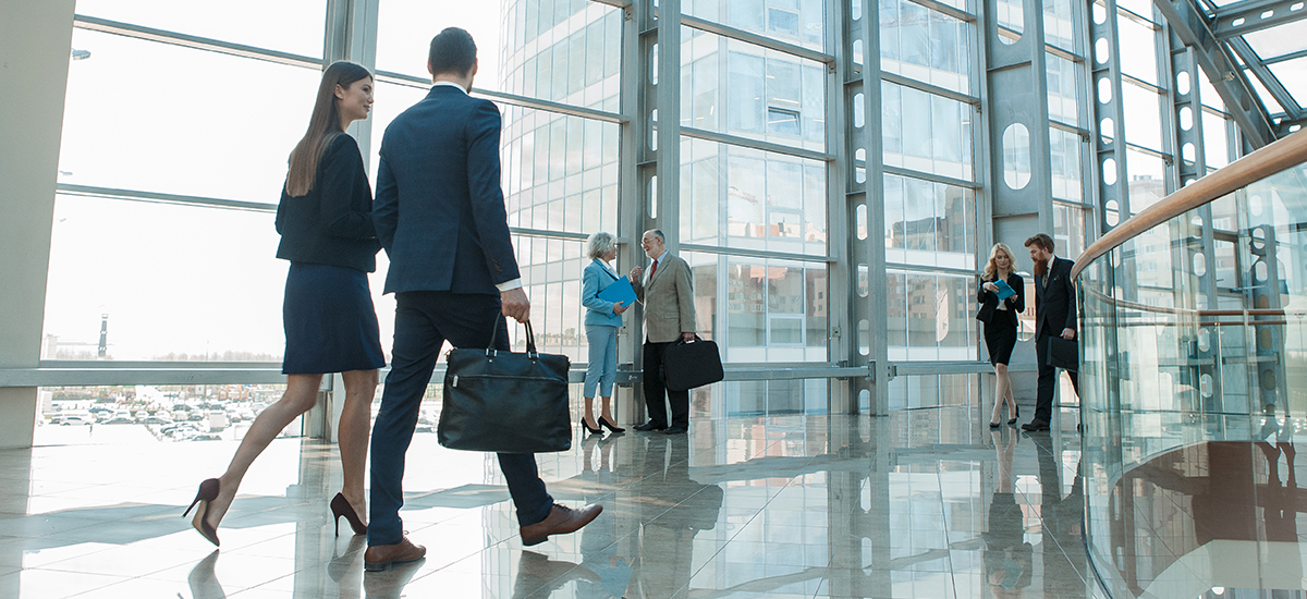 business man and woman walk down hallway in modern building