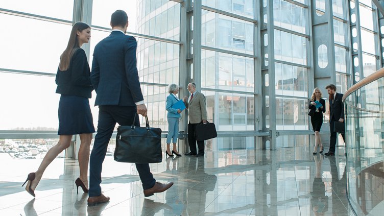 business man and woman walk down hallway in modern building