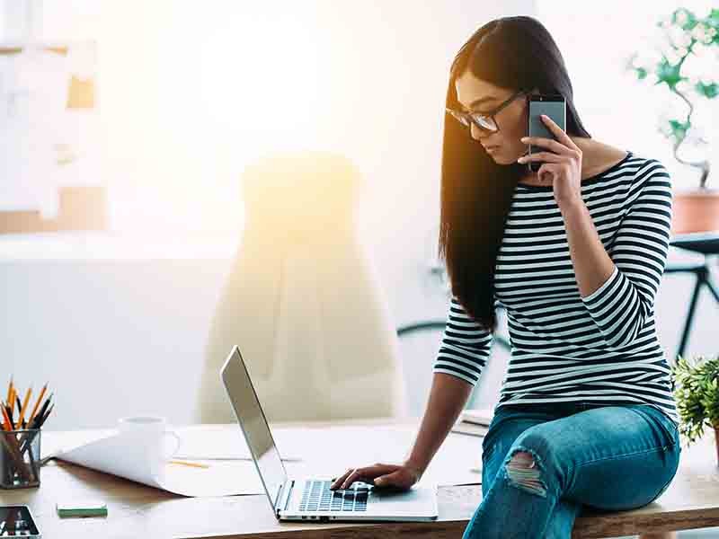 Woman on phone using laptop