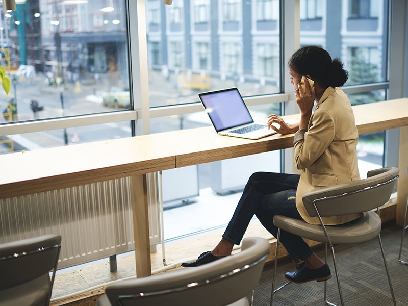 young woman on the phone in front of laptop