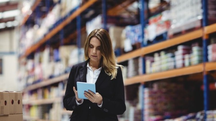 Employee of logistic warehouse using digital tablet for checking the stock