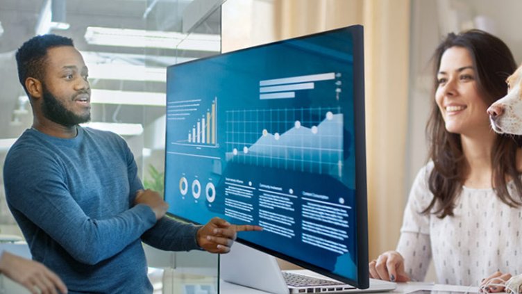 A male employee checking insights on computer screen while a female employee working from home - Future work environment