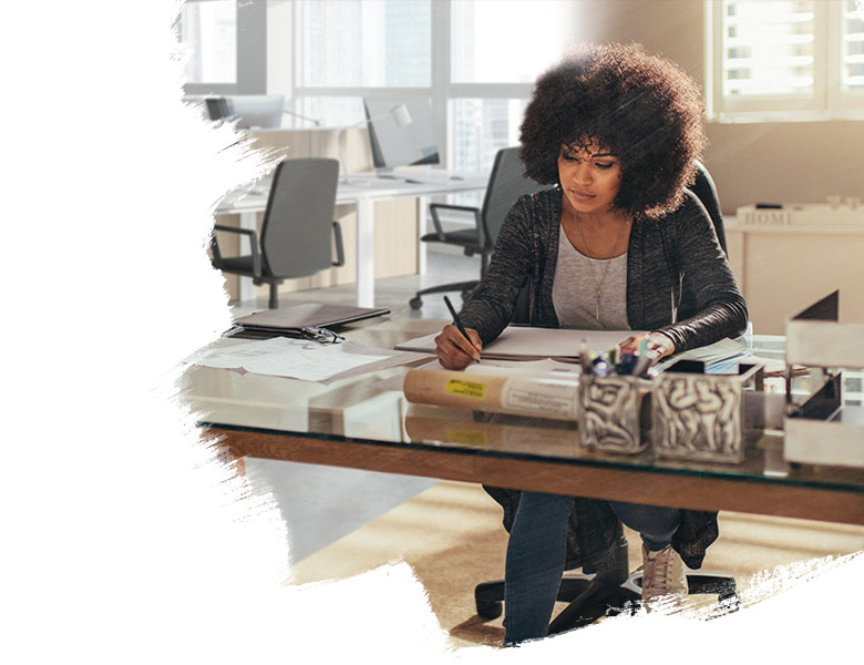 Woman sitting at desk writing on a notepad